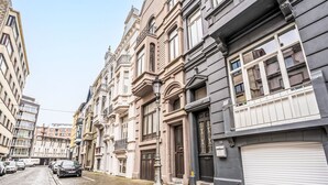 Una calle adoquinada flanqueada por edificios históricos, incluyendo uno a la derecha con una persiana cerrada.