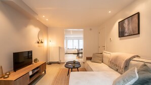 Una sala de estar moderna con un televisor de pantalla plana, un mueble de entretenimiento de madera y un sofá color beige.