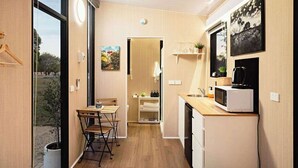 A compact kitchen with a dining area, a microwave, and a small sink. - Ballarat Bliss by Tiny Away (Cardigan)