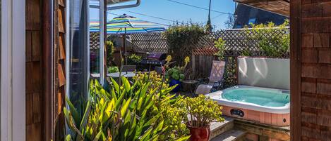 Un jardin avec un jacuzzi, une table de patio et une clôture en bois.