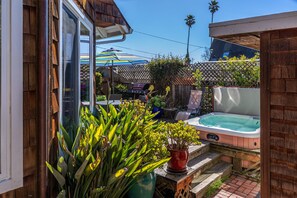 A backyard with a hot tub, a patio table, and a wooden fence. - Harbor home - with a hot tub! (Santa Cruz)
