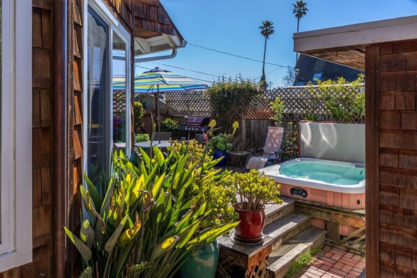 Un jardin avec un jacuzzi, une table de patio et une clôture en bois.