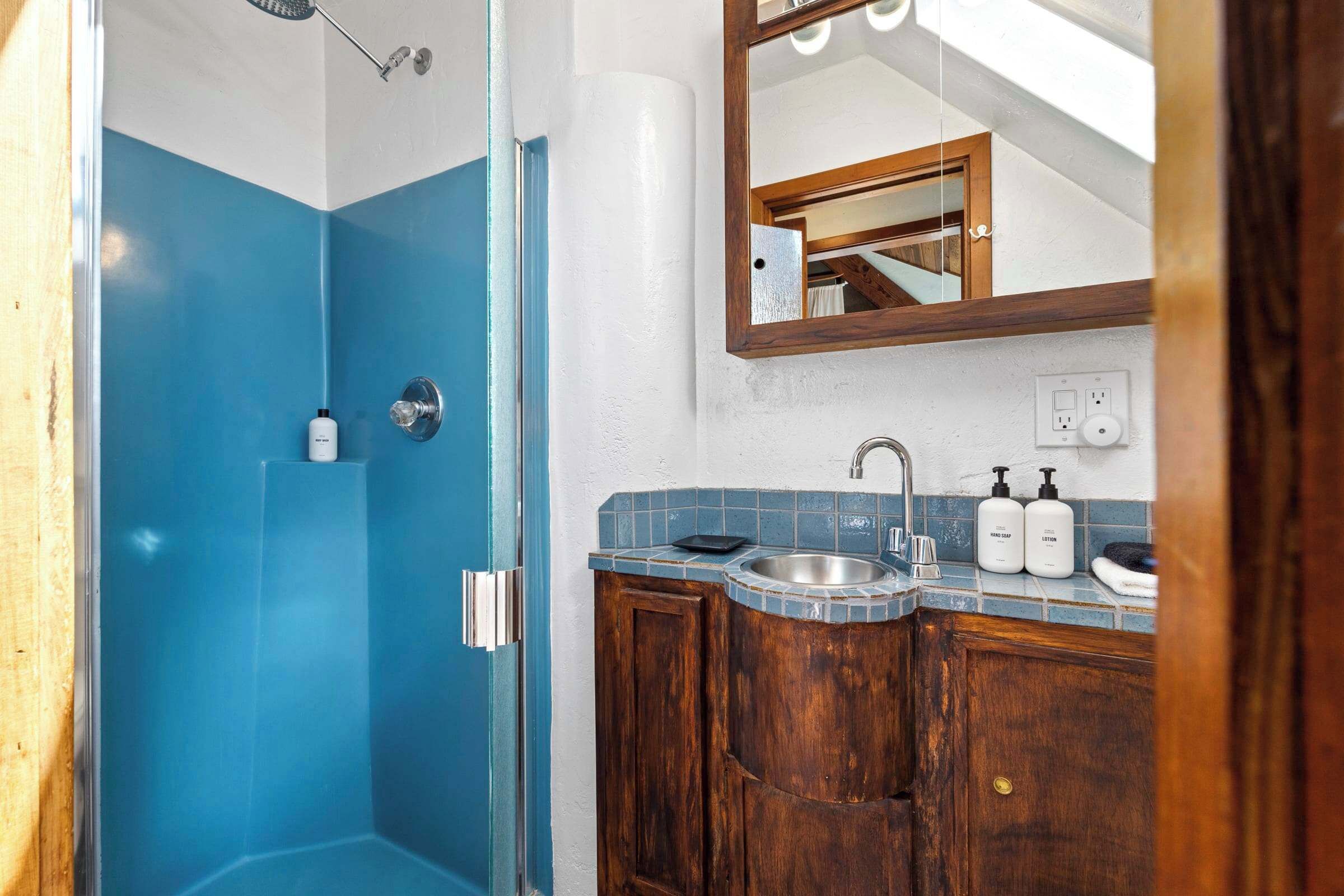 Un baño con ducha, lavamanos y espejo.