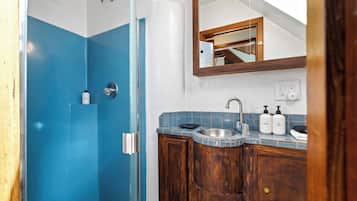 Un baño con ducha, lavamanos y espejo.