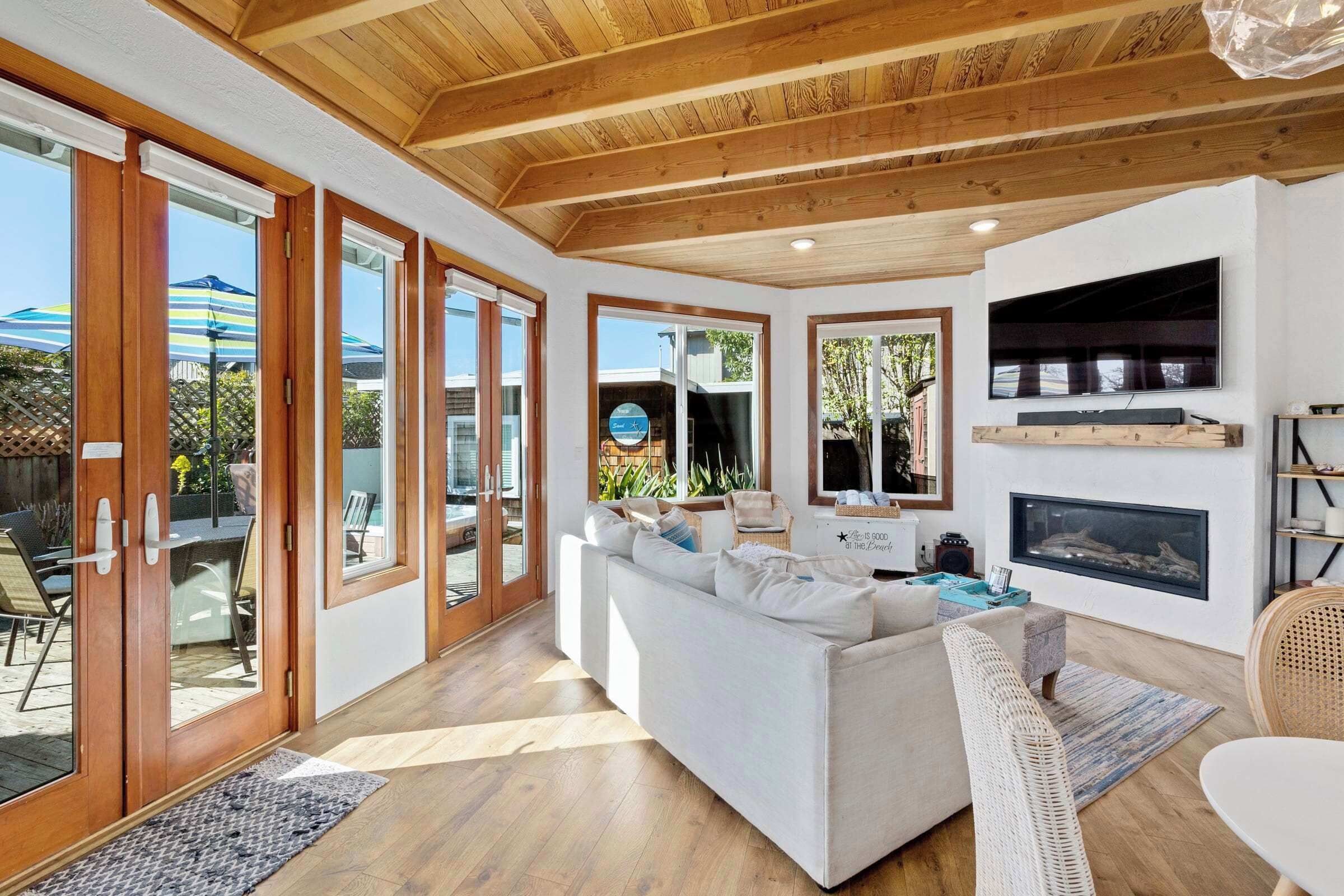 A spacious living room with a white sofa, wooden flooring, and a fireplace.