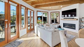Amplia sala de estar con sofá blanco, piso de madera y chimenea.