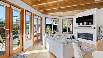 A spacious living room with a white sofa, wooden flooring, and a fireplace.