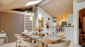 Een moderne keuken met witte kasten, een houten aanrechtblad en een hanglamp.