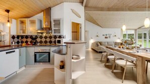 Een moderne keuken met een centraal eiland, ingebouwde apparatuur en een eetgedeelte met uitzicht.