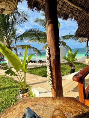 A tropical resort with a thatched roof, palm trees, and a view of the ocean. - Avo Boutique Hotel (Uroa)