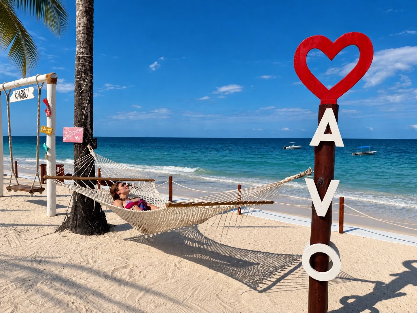 A hammock on a beach with a sign that reads 'AVO' and a heart-shaped sign above it.