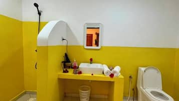 A bathroom with a yellow and white color scheme, a sink, a toilet, and a mirror.