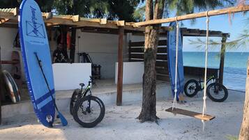 Un entorno costero con una estructura de madera, bicicletas y tablas de surf.