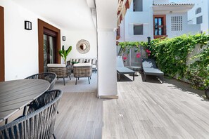 An outdoor patio with wicker furniture, a table, and a bench.