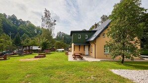 Un bâtiment doté d’un toit végétalisé et de murs de couleur beige, entouré d’une zone herbeuse avec des tables de pique-nique et une aire de jeux.