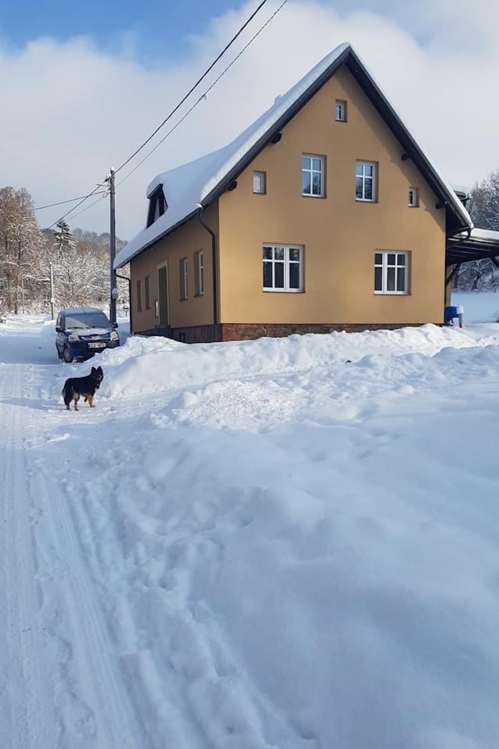A two-story house with a sloped roof, surrounded by snow.