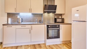 Une cuisine moderne avec des armoires blanches, un four encastré, un four à micro-ondes et une hotte de cuisinière en acier inoxydable.