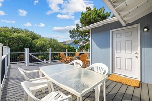 Une terrasse extérieure couverte, avec une table et des chaises, une porte blanche et une rambarde blanche.