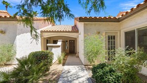 A house with a tiled roof, a stone fountain, and a pathway leading to the entrance. - Near Coachella Two Bedroom Two Bath Condo, Steps from the Pool & Spa, Desert Falls CC (Palm Desert)