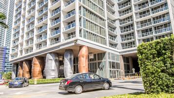 A modern hotel with a multi-story structure, large windows, and a prominent entrance with a unique architectural design featuring large, curved pillars.