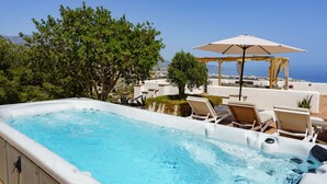 A hot tub with lounge chairs and an umbrella, overlooking a scenic view.