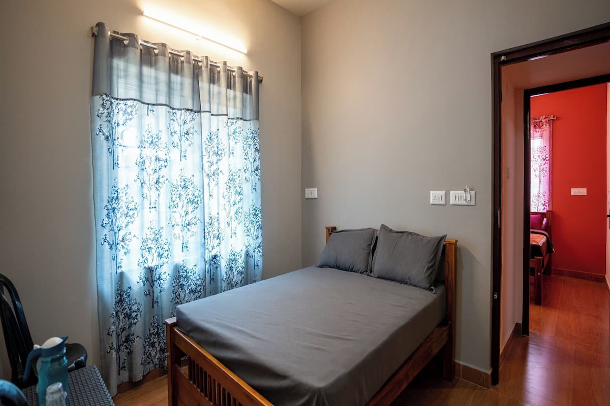 Un dormitorio con una cama de madera, una mesita de noche, una silla y una mesa con una lámpara.