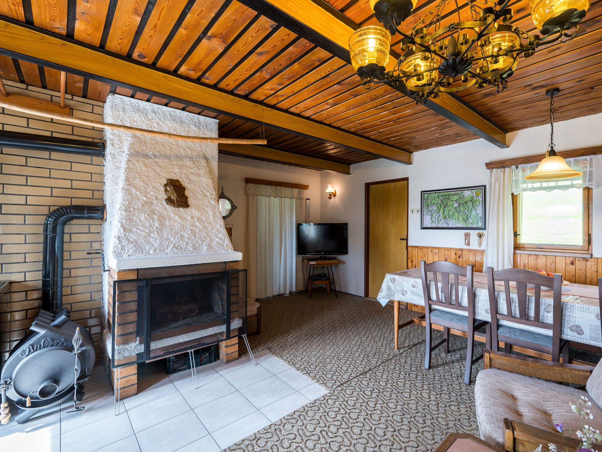 A cozy living room with a fireplace, a television, and a dining area with wooden furniture.