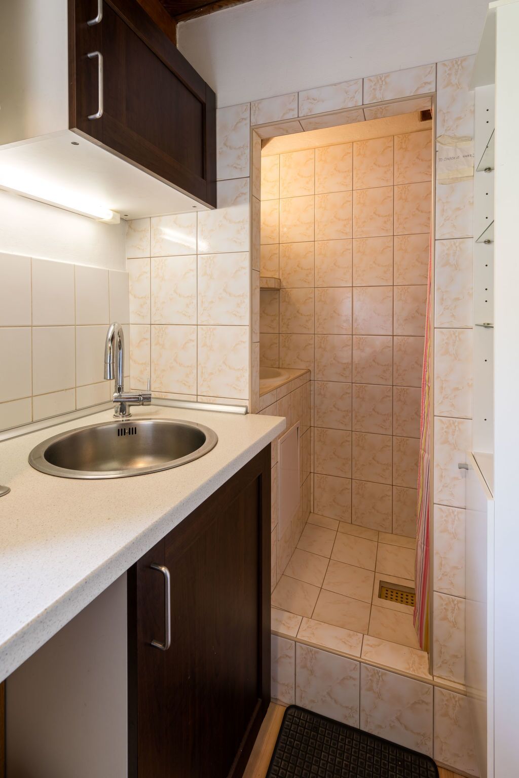 Un bagno moderno con lavandino, doccia e una piccola finestra.