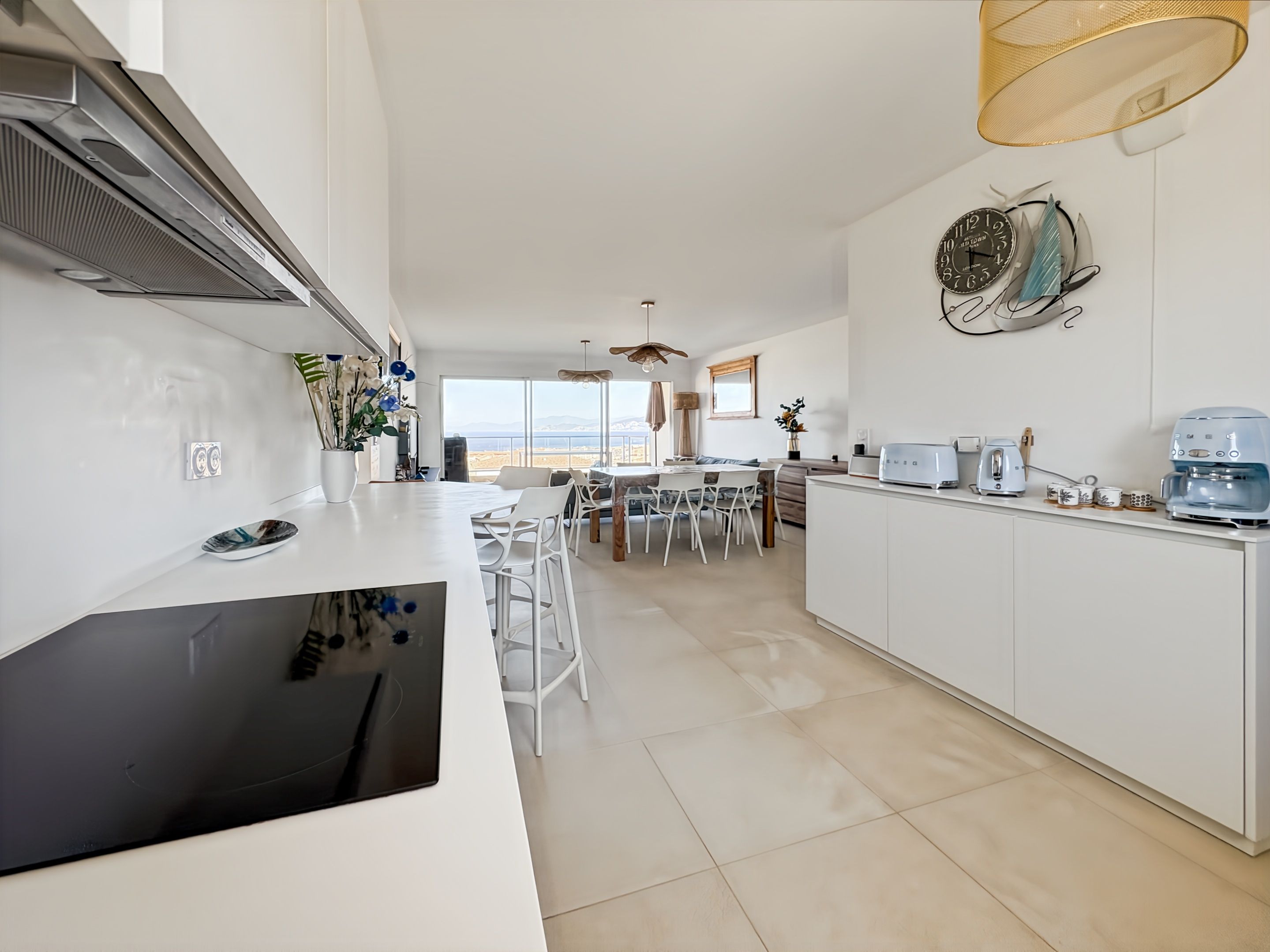 A modern kitchen with a central island, white cabinetry, and a view of the outdoors.