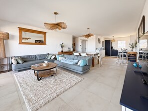 A modern living room with a sofa, coffee table, and dining area. - Appartement de 2 Chambres Pour 4 Personnes (L'Île-Rousse)