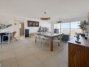A modern kitchen with a large island, white chairs, and a view of the sea. - Appartement de 2 Chambres Pour 4 Personnes (L'Île-Rousse)
