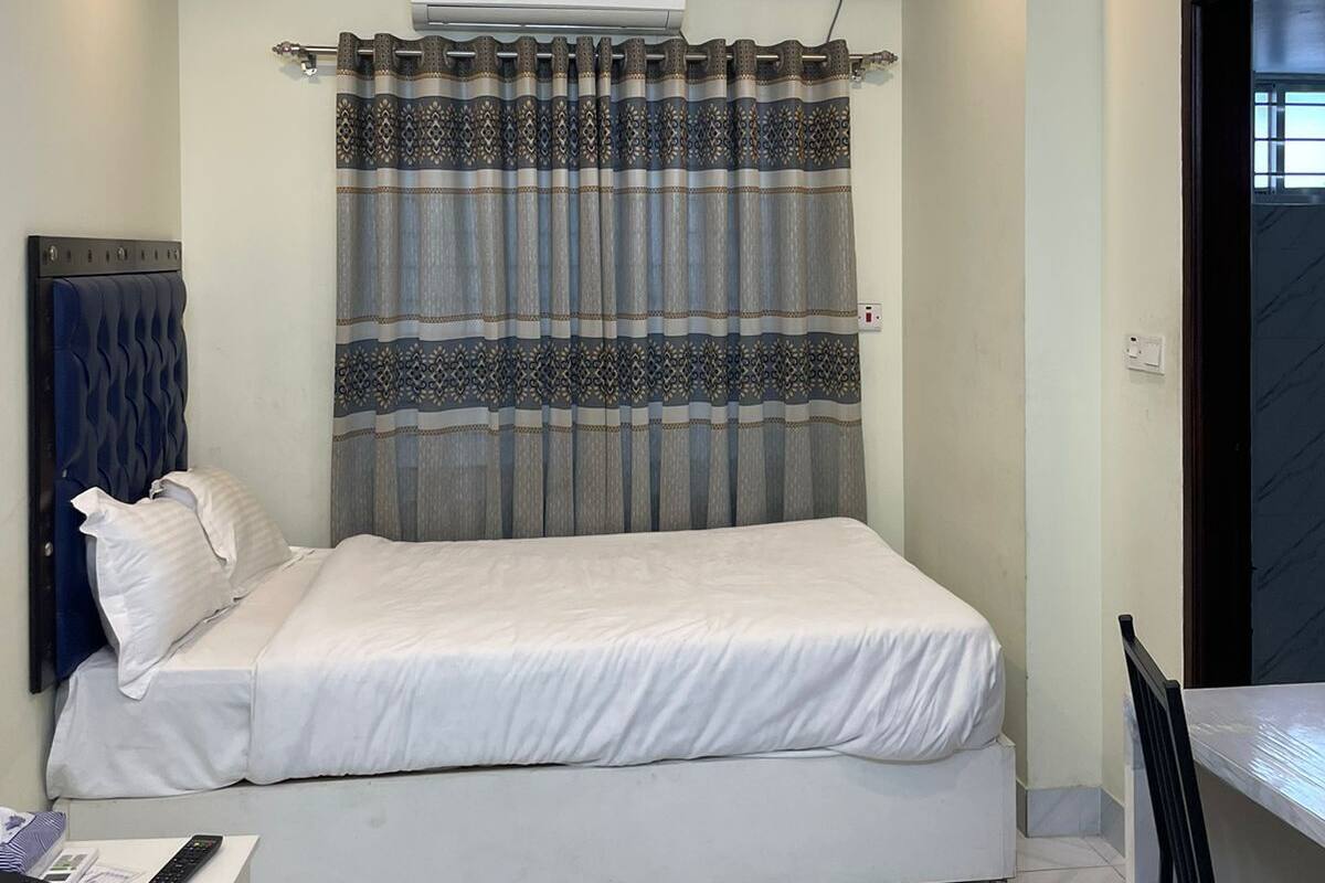Ein Schlafzimmer mit Bett, Schreibtisch, Stuhl, Deckenventilator und Klimaanlage.