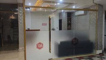 A hotel reception area with a glass door, a push bar, and a logo on the door.