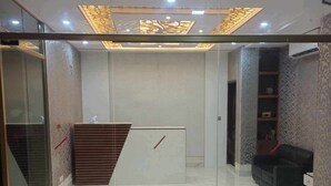 Zona de recepción con separador de vidrio, mostrador de recepción, piso estampado y pared con diseño.