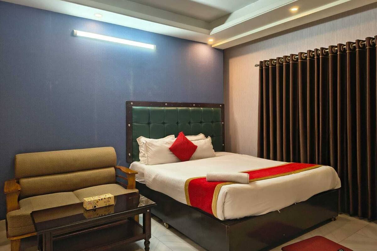 Ein Hotelzimmer mit einem Bett, einem Sofa, einem Couchtisch und einem fenster mit Vorhängen.