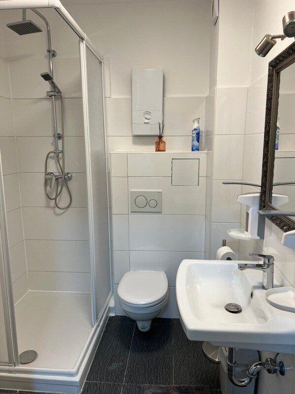 A modern bathroom with a shower, toilet, and sink. - Komfortable Wohnung in 1A Lage (Herne)