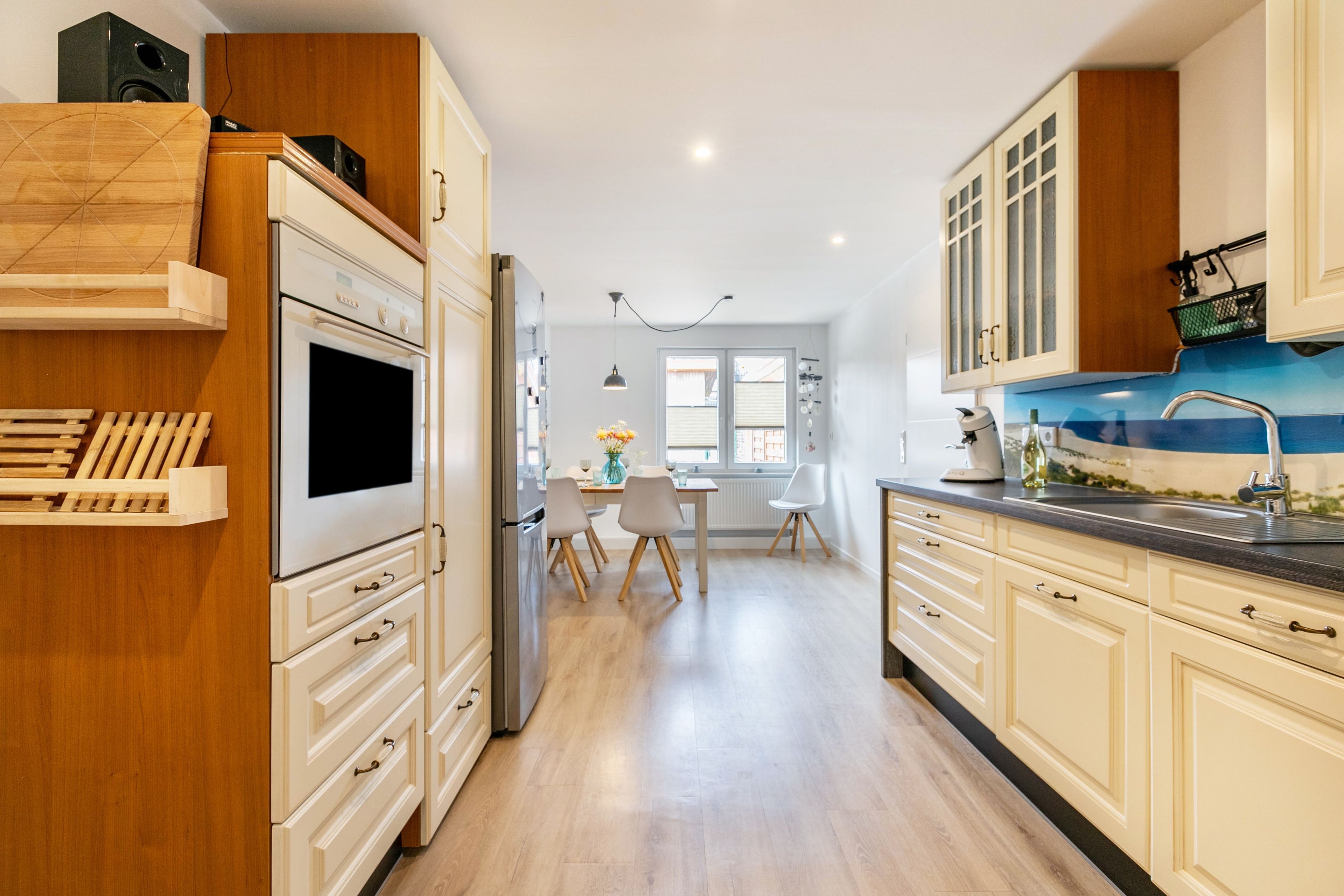 Eine moderne Küche mit Holzschränken, einem eingebauten Backofen und einem Essbereich mit Tisch und Stühlen.