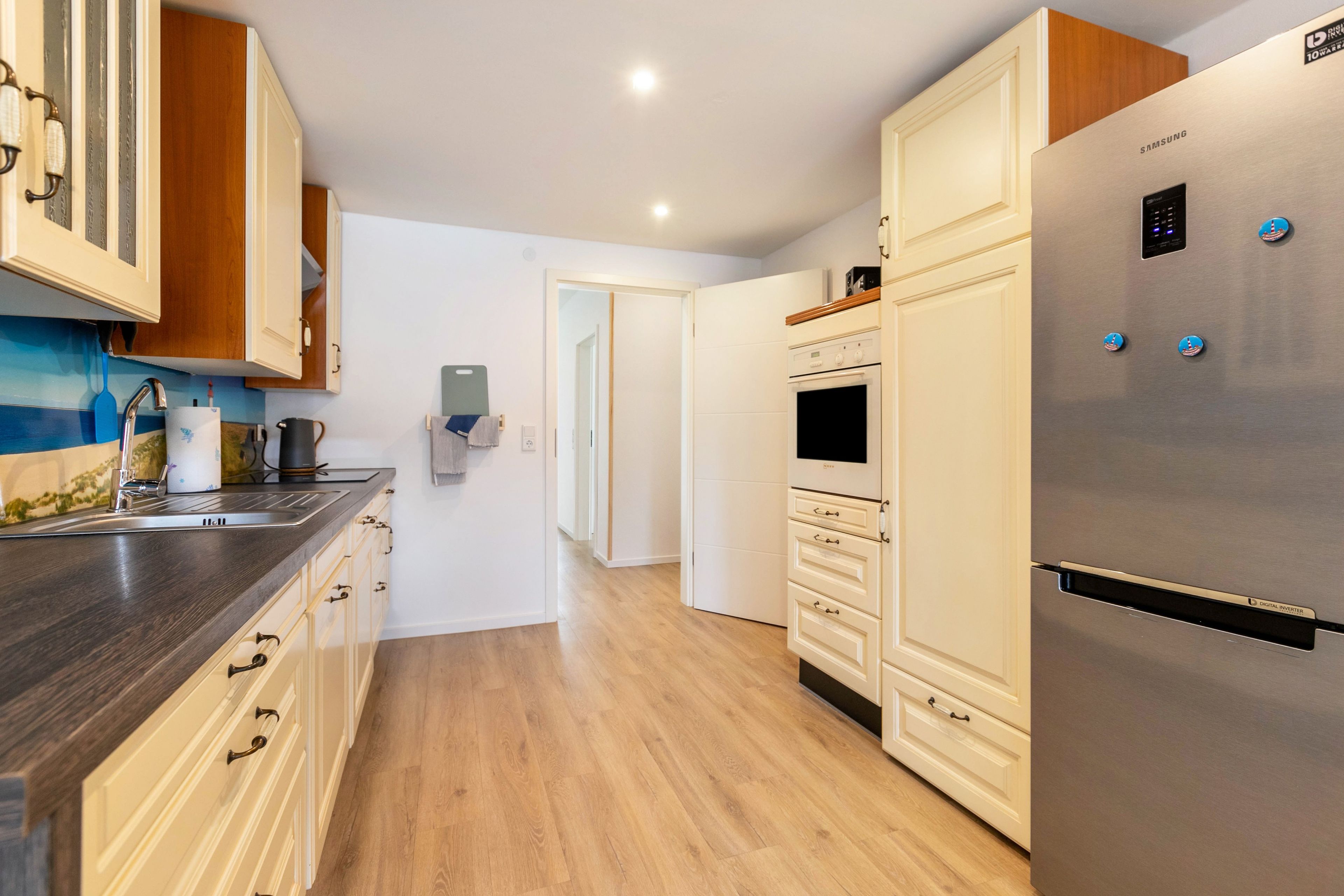 Een moderne keuken met een roestvrijstalen koelkast, houten kastjes en een inbouwoven.