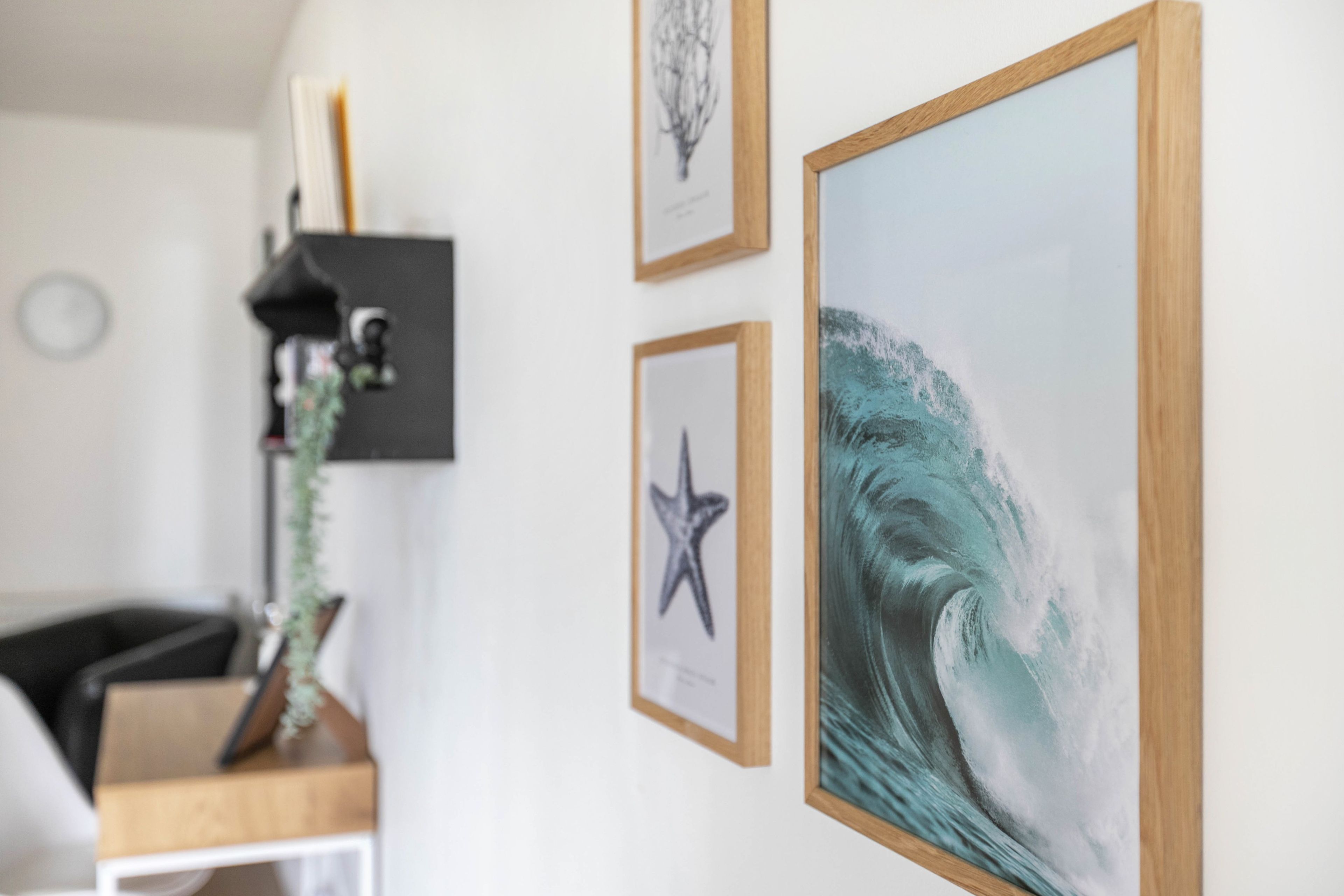 Una habitación con un escritorio, una silla, una planta y cuadros en la pared.