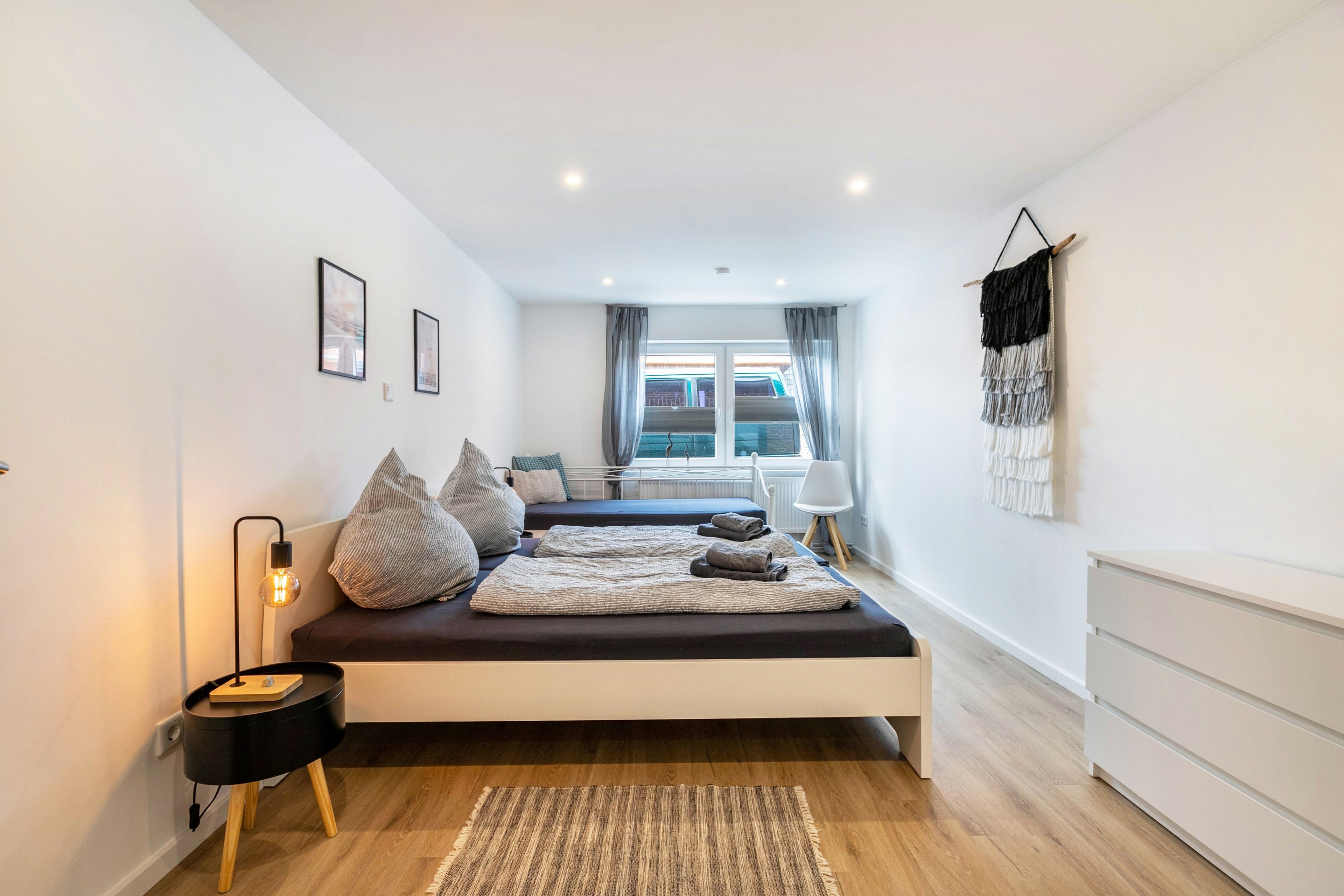 A modern bedroom with a bed, bedside tables, a lamp, and a view of the outside.