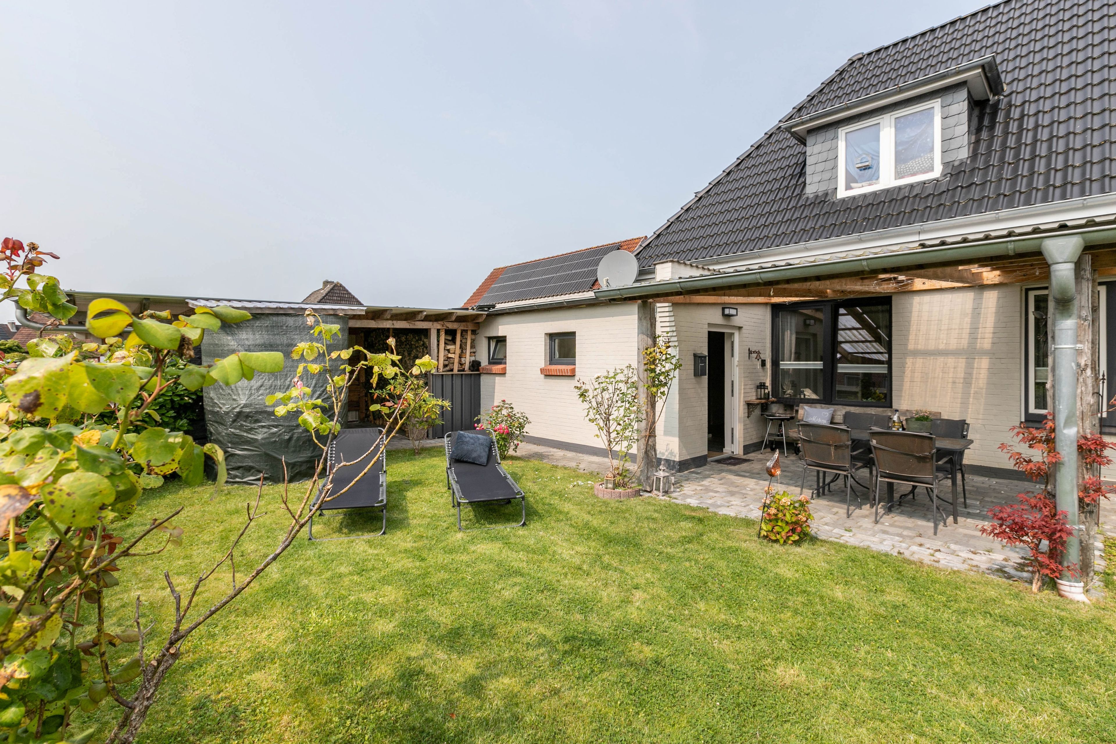 A residential property with a covered patio, outdoor seating, and a garden area.