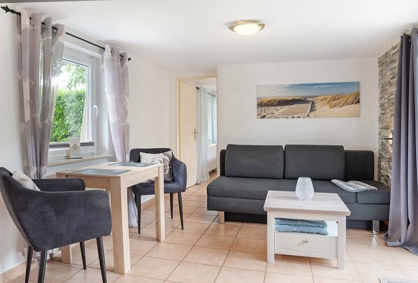 Un salon avec un canapé, une table à manger entourée de chaises, une table basse et un tableau accroché au mur.