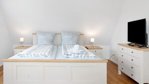 Makuuhuoneessa on sänky, kaksi yöpöytää, jalustalla oleva televisio ja lipasto.