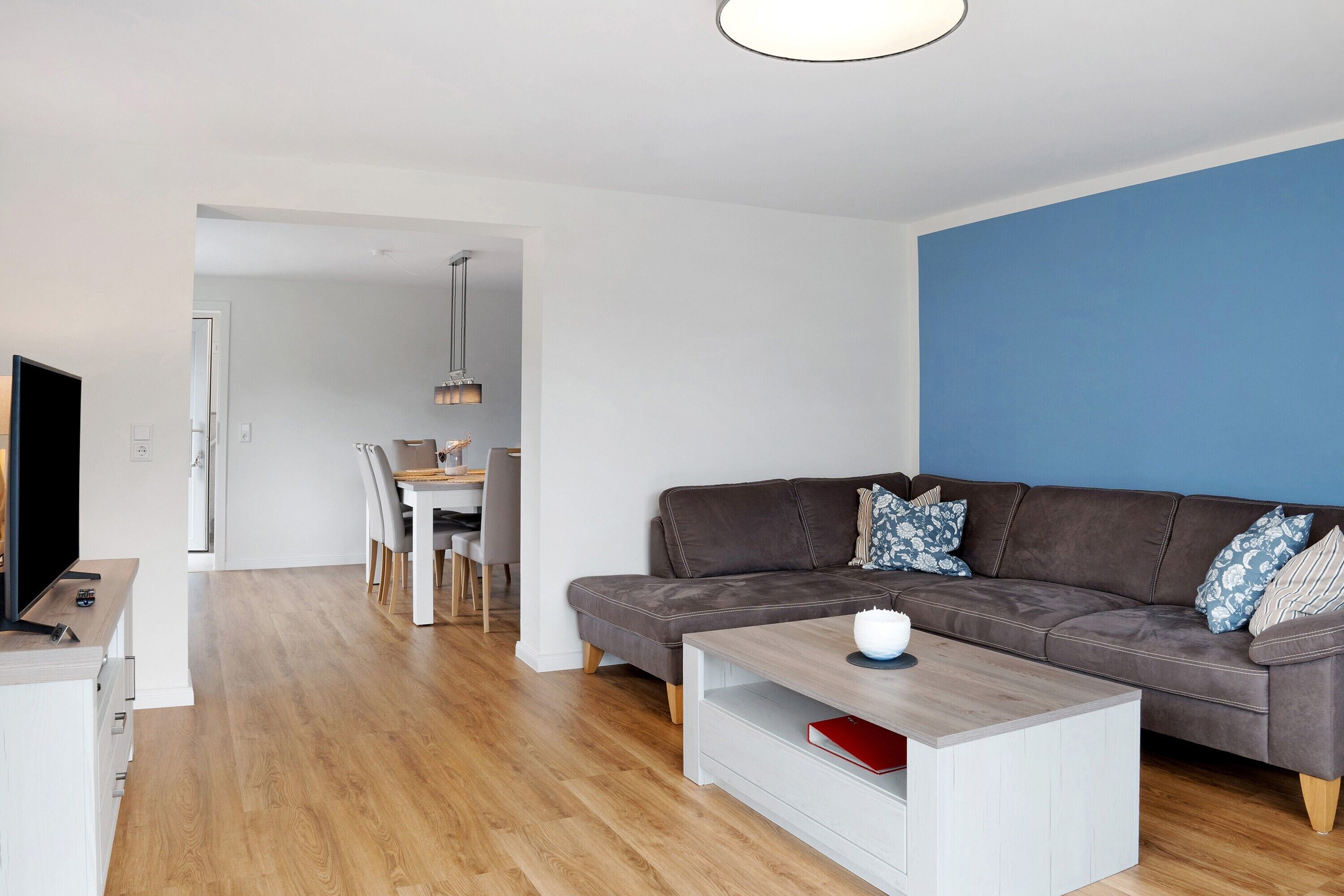 A modern living room with a brown sofa, a coffee table, and a TV.