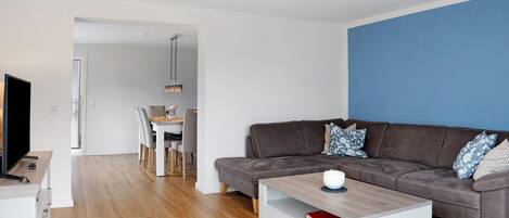 A modern living room with a brown sofa, a coffee table, and a TV.