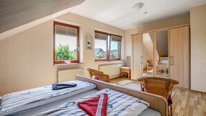 Quarto com duas camas, janela, cadeira e guarda-roupa.