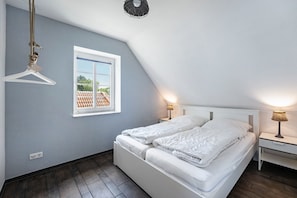 A bedroom with a bed, bedside tables, a hanging chair, a window, and a ceiling light fixture.