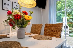 Un tavolo da pranzo con un vaso di fiori, sedie in vimini e una lampada in vimini.