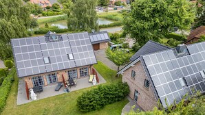 Ein Wohngebäude mit Solaranlage auf dem Dach, einer gepflasterten Auffahrt und einem gepflegten Rasen.