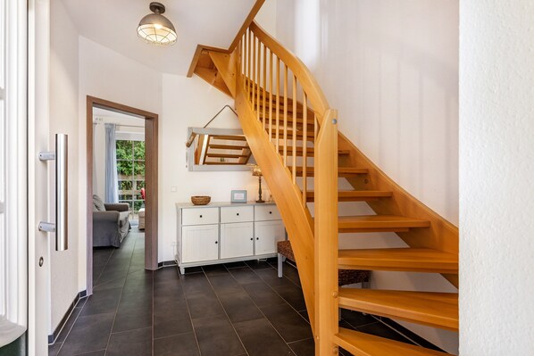 A wooden staircase leading to a landing with a white cabinet and a hanging light fixture.